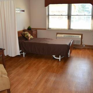 A healthcare facility room with a single bed and window.