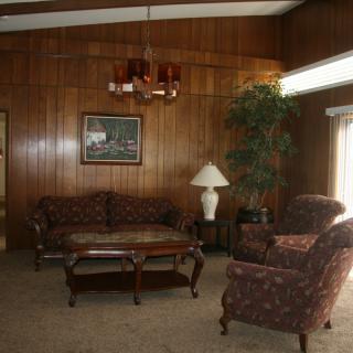 Cozy living room with wood paneling and classic furniture.