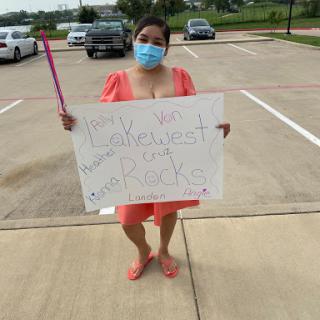 A participant holding a sign while wearing a mask, advocating for a cause in an outdoor setting.