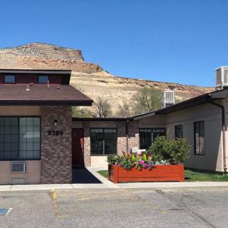 A roadside motel with a mountainous landscape in the background under a clear blue sky.