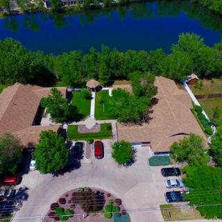Aerial view of a serene landscape featuring buildings surrounded by lush greenery and a calm water body.