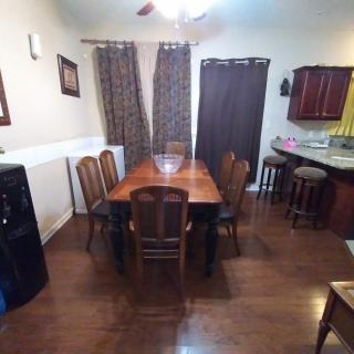 A cozy dining area with a large wooden table and chairs, adjacent to a kitchen space.