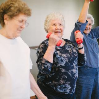 Seniors enjoying a lively exercise session with dumbbells, promoting health and fitness.