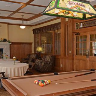 A cozy game room featuring a pool table with a classic chandelier and comfortable seating.