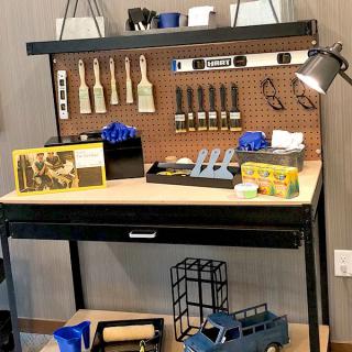 A workbench with various tools and gifts, including paintbrushes and a toy truck.