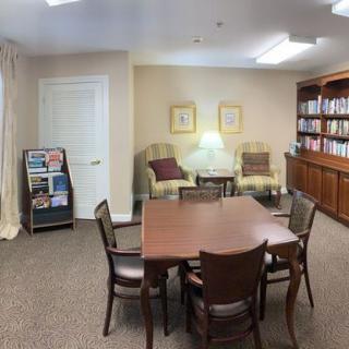 A cozy reading area with a table, chairs, bookshelves, and comfortable seating.