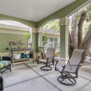 A cozy covered patio with comfortable seating and potted plants, perfect for relaxation.