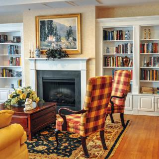 A cozy living room with a fireplace surrounded by built-in bookshelves and patterned armchairs.