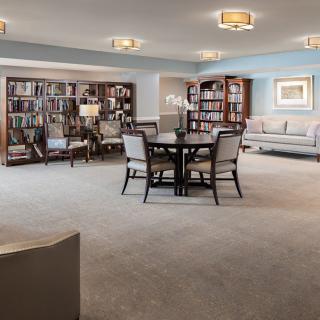 A cozy and spacious library room with bookshelves, a reading table, and comfortable seating.