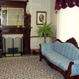 A vintage living room featuring antique furniture and a fireplace.