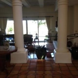 A spacious living room with large windows, columns, and comfortable furniture.