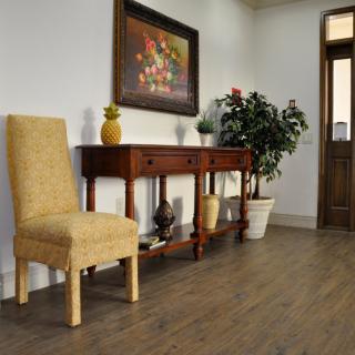 A cozy interior featuring a wooden console table with decorative items and a plant, alongside an upholstered chair.