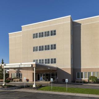 A modern hospital building featuring a welcoming entrance under a clear blue sky.