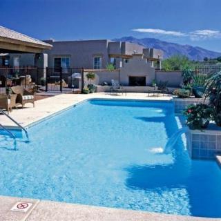 A luxurious outdoor swimming pool with a scenic mountain backdrop on a sunny day.