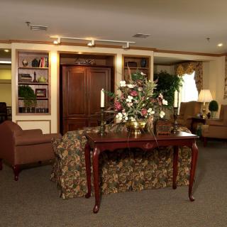 A cozy living room with elegant decor, featuring a table adorned with flowers.