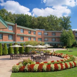 A hotel with an outdoor patio area surrounded by colorful flowers and lush greenery.
