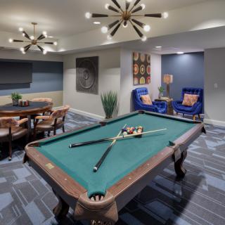 A stylish game room featuring a pool table and modern seating area with elegant lighting.