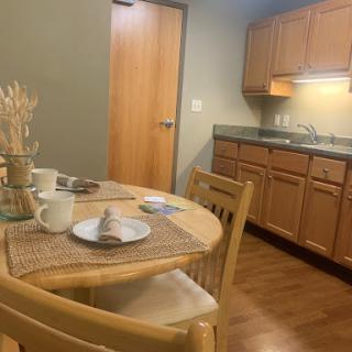 A cozy dining space featuring a wooden table set for a meal, surrounded by warm tones and modern kitchen cabinetry.