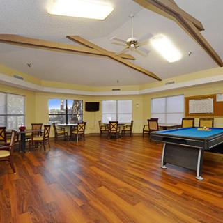 A spacious game room with a billiards table, hardwood floors, and ample seating.