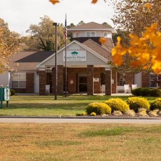 A brick building surrounded by autumn foliage and a well-maintained lawn.