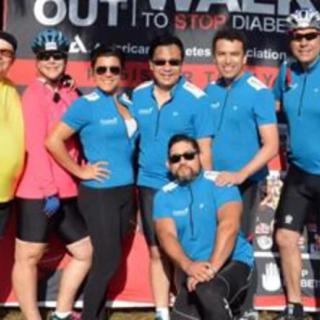 A group of people posing together at a diabetes awareness event, wearing matching blue shirts.