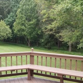 A wooden deck overlooking a grassy backyard with trees in the background.