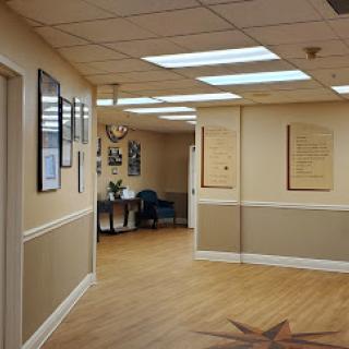 A well-lit office hallway featuring wall decorations and a comfortable seating area.