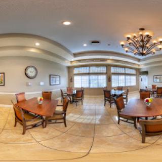 A spacious dining area with elegant decor, featuring wooden tables and chairs, accented by a beautiful chandelier.