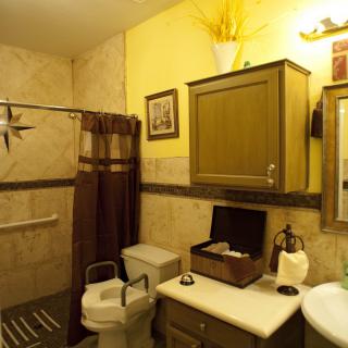 A cozy bathroom featuring a toilet with a raised seat, sink with cabinet, and a decorative shower curtain.