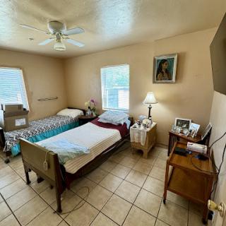 A cozy bedroom featuring two beds, a bedside lamp, and artwork on the walls.