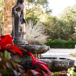 A serene garden fountain with a classical statue and vibrant foliage.