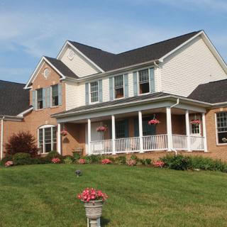 A suburban brick house with a large front lawn and garden.