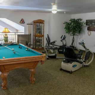 A recreational room featuring a pool table and exercise equipment.