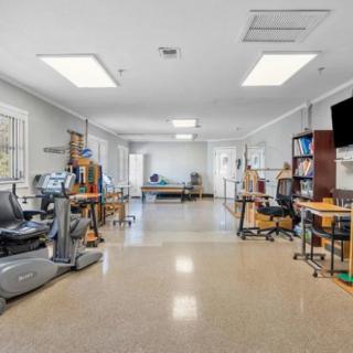 A spacious therapy room equipped with various exercise machines and tools for rehabilitation in a healthcare facility.