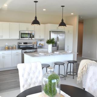 A modern kitchen with white cabinets, a central island, and sleek pendant lighting.