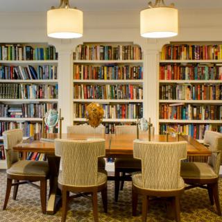 A cozy study room with bookshelves, a wooden dining table, and chairs.