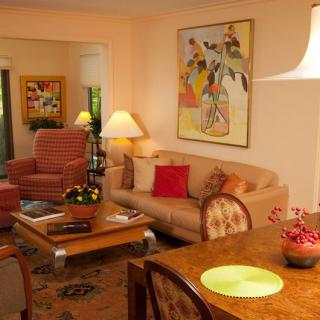 A cozy living room with warm decor, featuring a comfortable sofa, artwork on the wall, and elegant lighting.