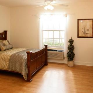 A cozy bedroom with wooden flooring, featuring a bed and a window letting in natural light.