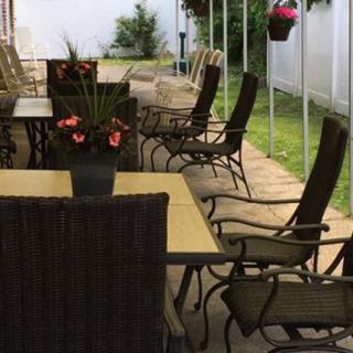 Outdoor patio seating area with tables and chairs surrounded by plants.