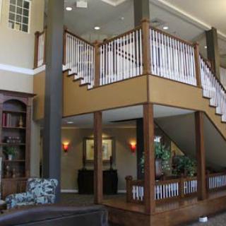 A spacious living area featuring a prominent wooden staircase and balcony.