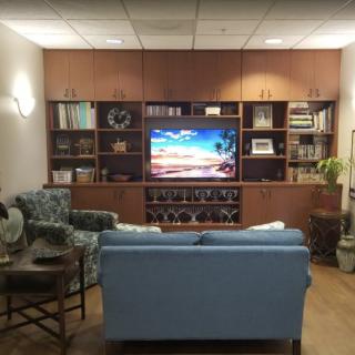 A cozy living room with a large entertainment center, featuring a television, bookshelves, and comfortable seating.