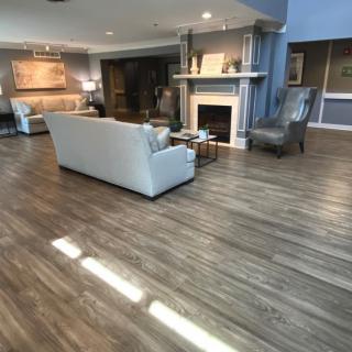 A spacious and elegantly decorated living room featuring wood flooring, a cozy sofa, and a fireplace.