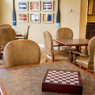 A cozy game room with a chess board on the table and comfortable seating, adorned with colorful artwork on the walls.