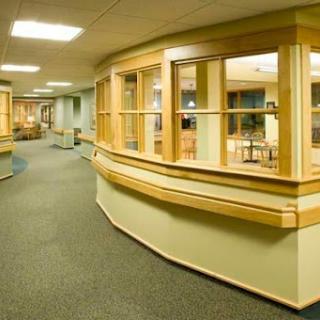 A modern hospital corridor featuring wooden accents and ample lighting.