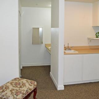 Interior view of a home featuring a small kitchenette and hallway leading to a bathroom.
