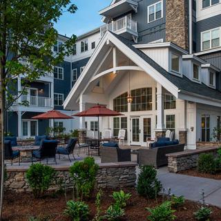 A modern apartment building with a landscaped patio and outdoor seating area.