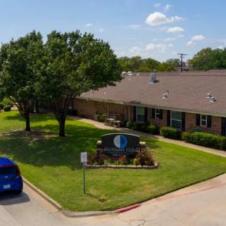 A healthcare clinic building with a surrounding lawn and parking area.