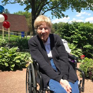 A joyful senior woman enjoying a sunny day in the garden, sitting in her wheelchair.