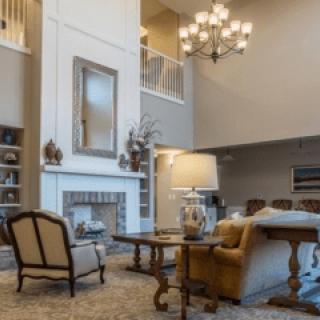 A spacious living room with elegant furnishings and a chandelier.