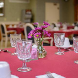A beautifully set dining table with crystal glasses and a vase of flowers in a restaurant.